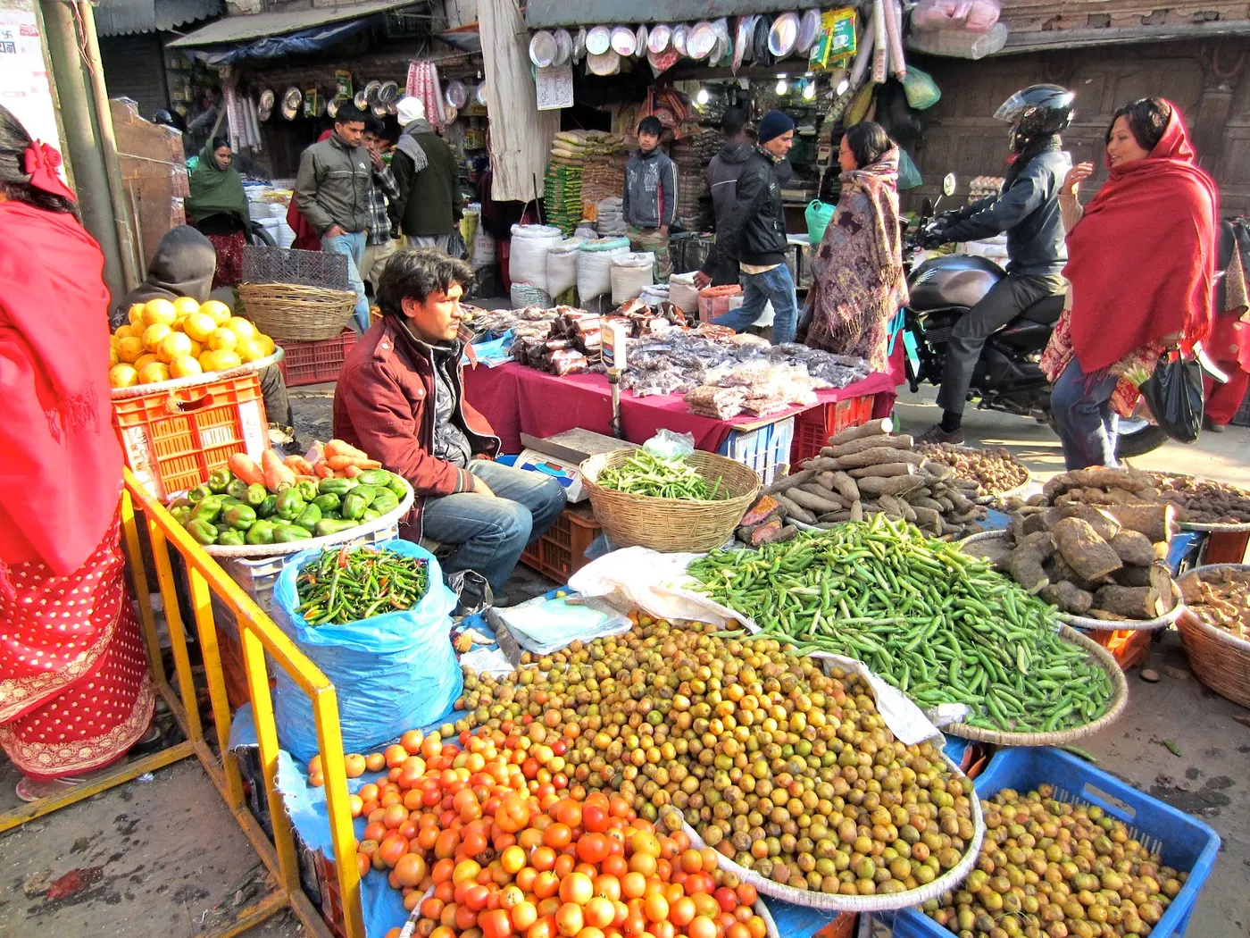 Vendors selling two big baskets of lapsi fruits with other vegetables - a great social atmosphere in the Asan Tole area of Kathmandu.