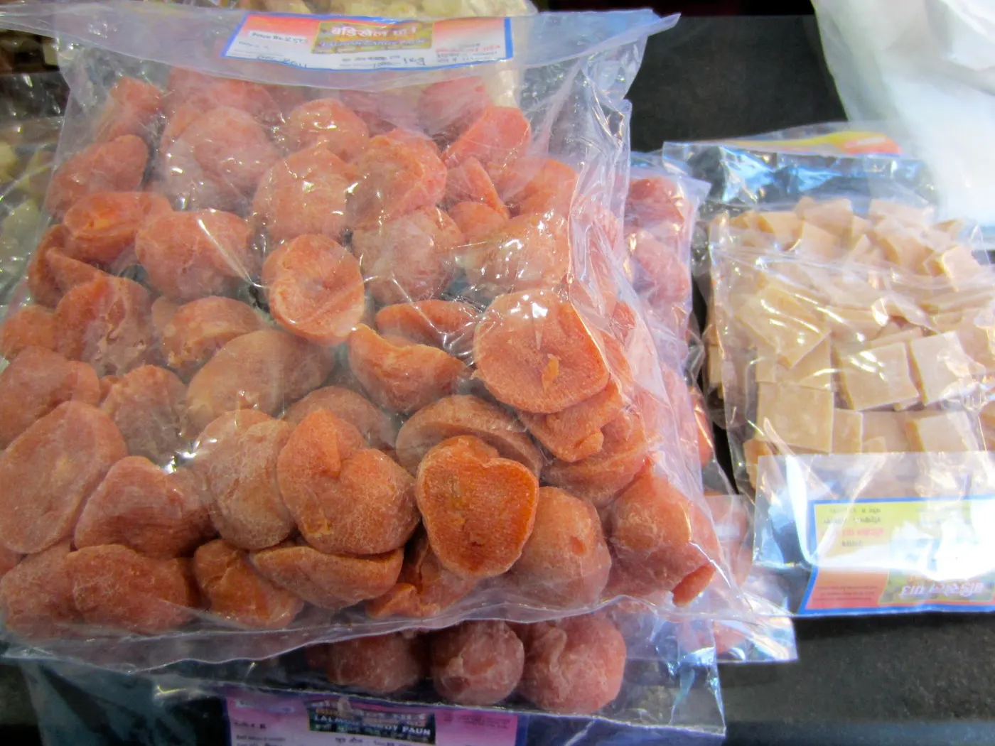 Commercially made, packaged lapsi nuggets, in several different shapes and sizes are sold in the markets. On the left (orange) is a spicy one, and on the right (white) is made with a mixture of fruit and sugar only.