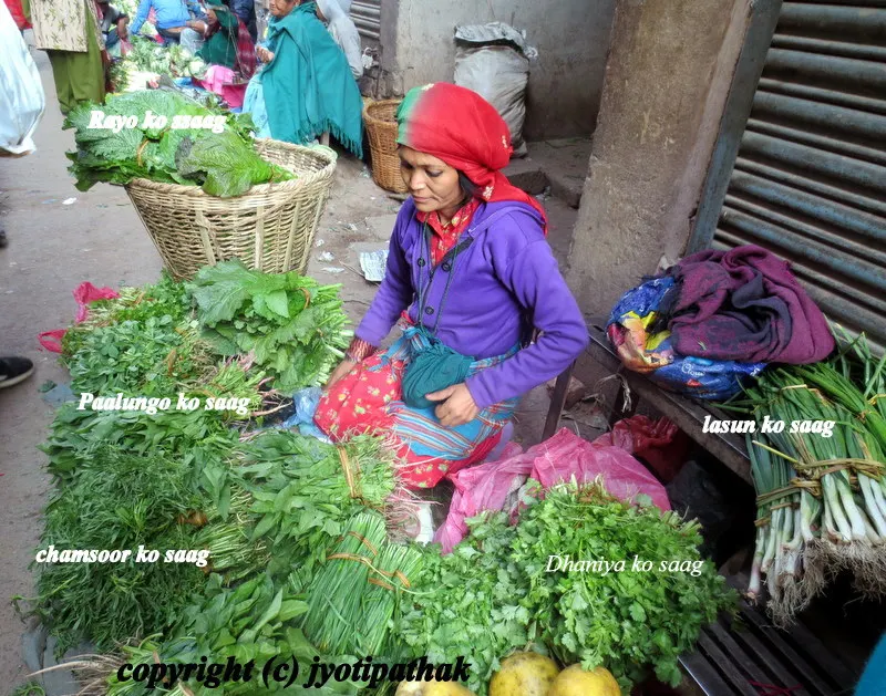 A local vegetable vendor is busy rearranging freshly brought greens and offering her goods for sale.