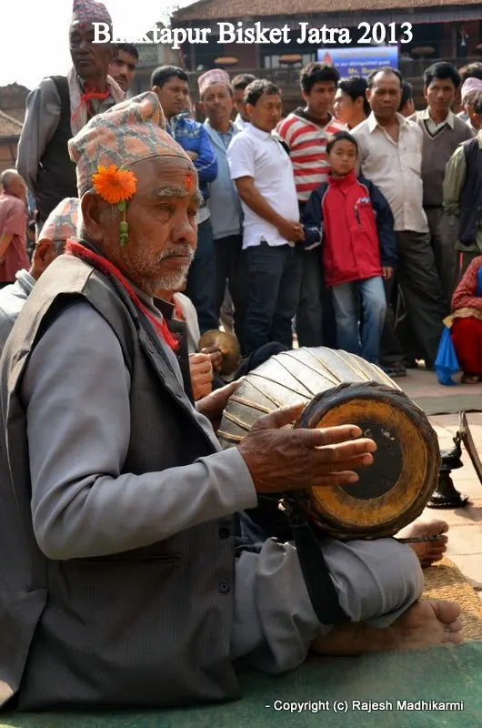... the leading musician with dhakaa topee (Nepali traditional hat), flower in his ears, busy playing the classic instrument tabalaa in the packed courtyard of Bhaktapur festival site ...