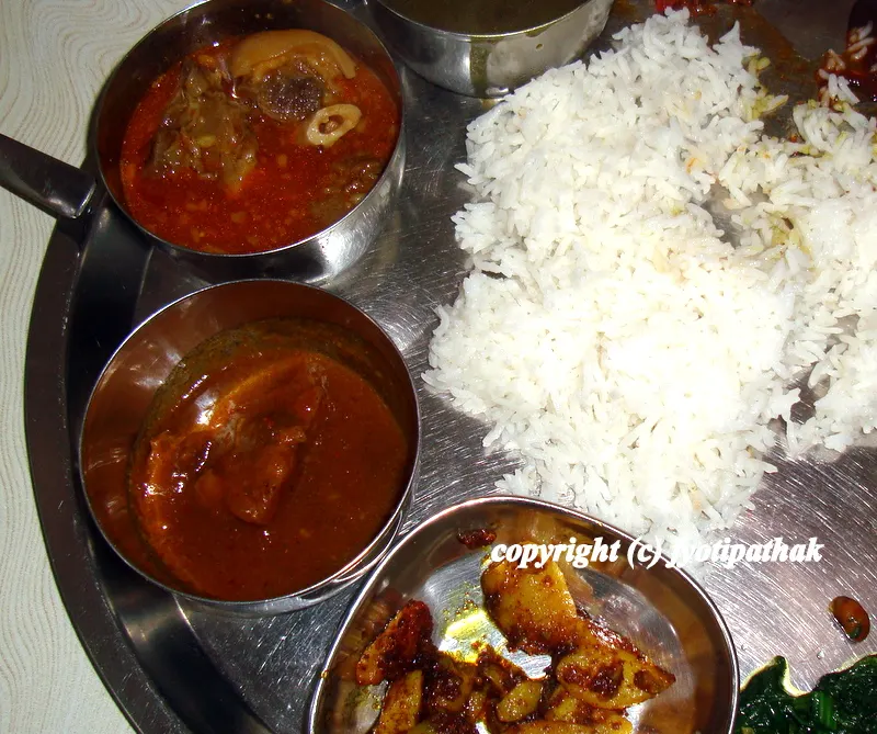 A rusty and authentic soupy goat curry served with a selection of fresh vegetables, assortment of pickles and a freshly steamed rice.