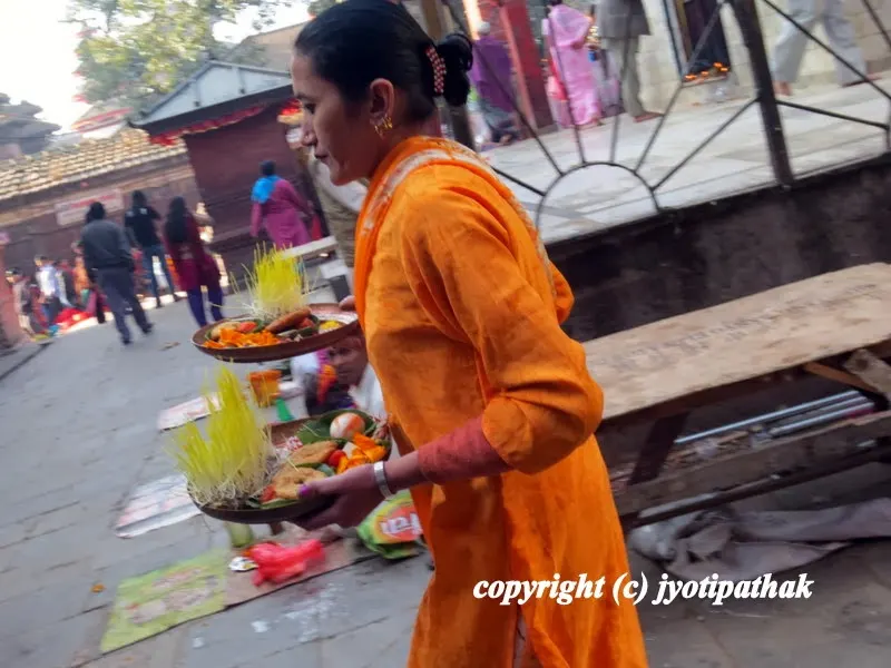 A young Nepalese women with two tray full of sacred offerings is on her way to Shova Bhagawati temple.