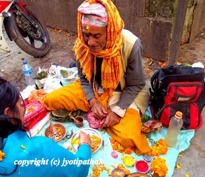 A Brahmin priest outside the temple is offering a prayer and blessing to a young devotee.