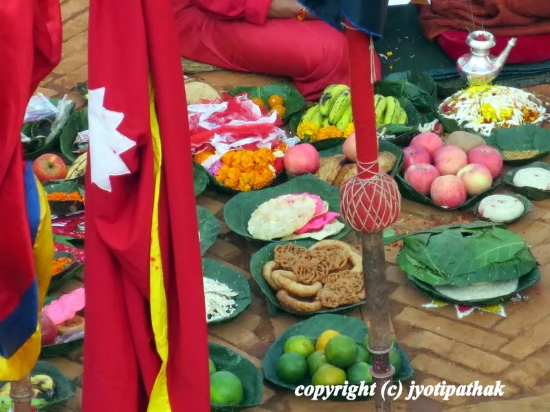 Large supply of sacred offerings in several leaf plates (flowers, fruits, Nepali sweets, raw rice, red and white fabric, oil-fed lamp) at Kot courtyard