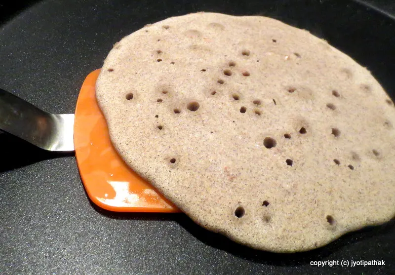 Watch for bubbles on the surface of the bread, then gently flip the phaapar ko roti